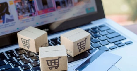 Image of a person holding a tablet with a online grocery management system while standing in a grocery aisle.